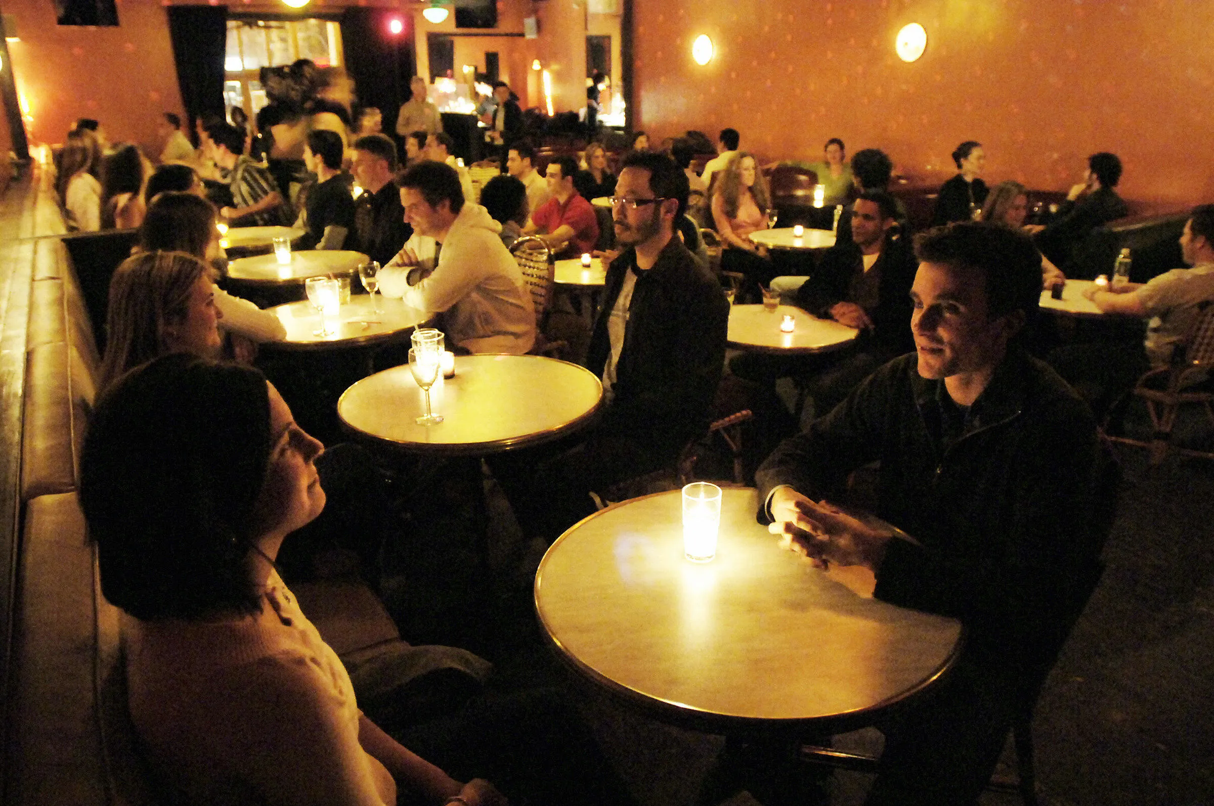 A full room of singles talking across candlelit tables